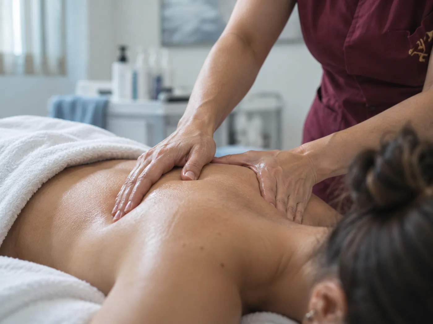 Un massaggio in corso nella cabina relax: mani dell'operatrice, atmosfera calda e curata.